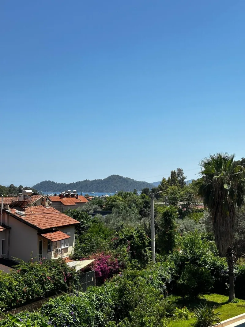 Göcek tesisinden palmiyeli bahçe ve uzak marina manzarası