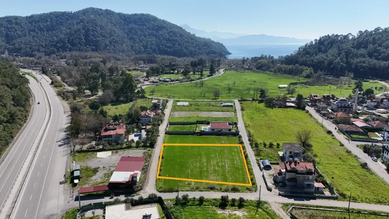 İnlice 2000 m² arsa havadan çekim; turuncu işaretli düz parsel, solunda otoyol ve körfeze açılan vadi