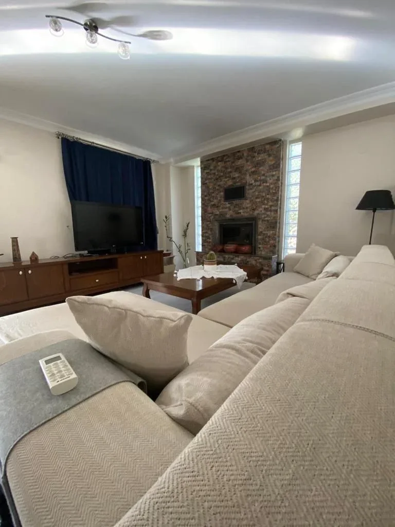 Göcek İnlice taş villada taş şömineli salon; krem koltuk takımı ve cam blok pencereler