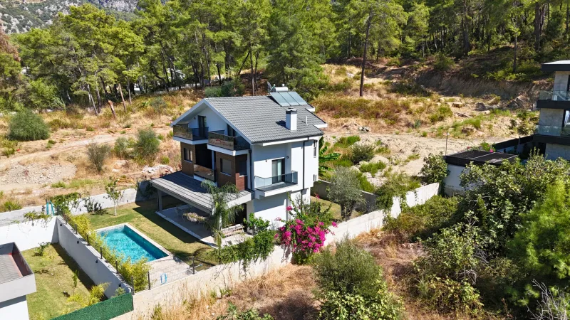 Çam ormanı içinde özel havuzlu beyaz cepheli satılık villa; drone perspektif ve begonvil, Göcek