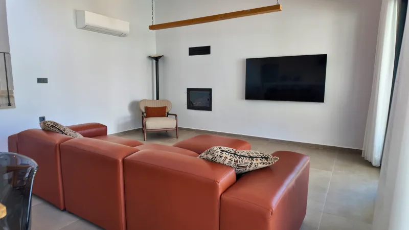 Terrakota deri koltuk ve duvara monte TV li modern oturma odası; şömine köşesi, Göcek satılık villa