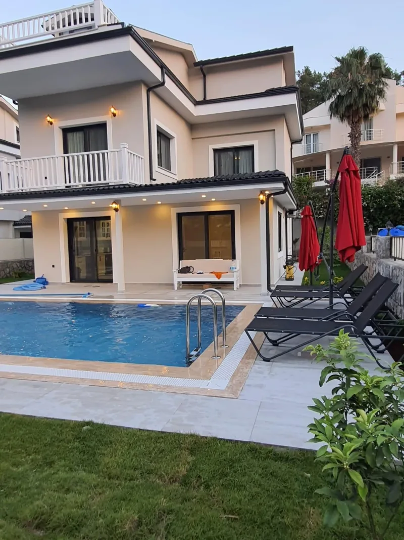Göcek merkez kiralık villa gün batımında havuz başı, ışıklı teras ve bahçe